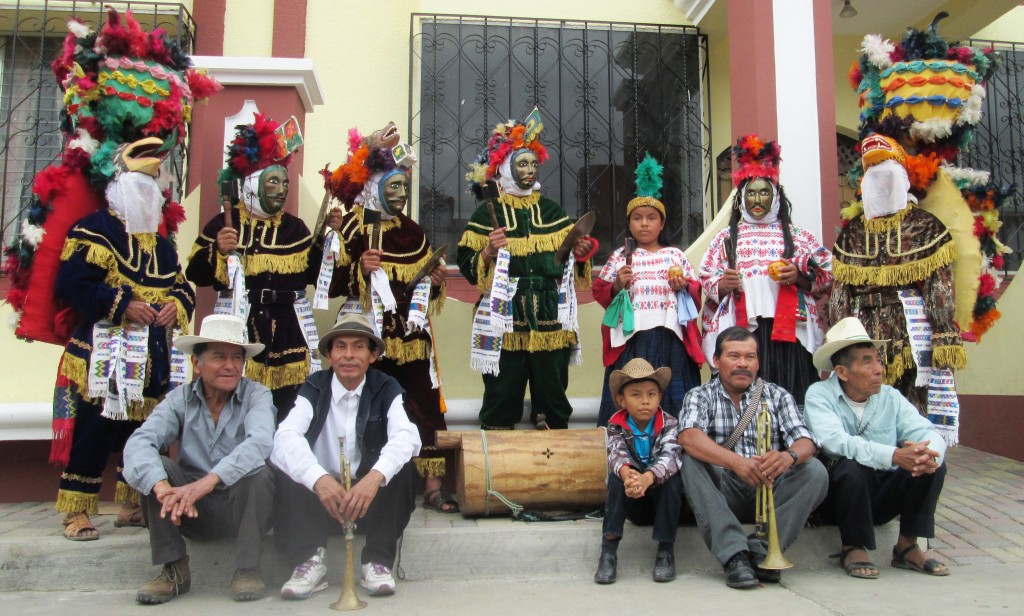 Standing: Kot (Eagle warrior), K’iche`Achi (high rank warrior), Rab’inal Achi (high rank warrior),  Job Toj (governor), Yamanik (governor’s wife) Mun (servant) B’alam (jaguar warrior). Sitting: Person in charge of the costumes; musicians: trumpet player, child who plays the Tun, trumpet player, and Ajq’ij (Maya shaman).